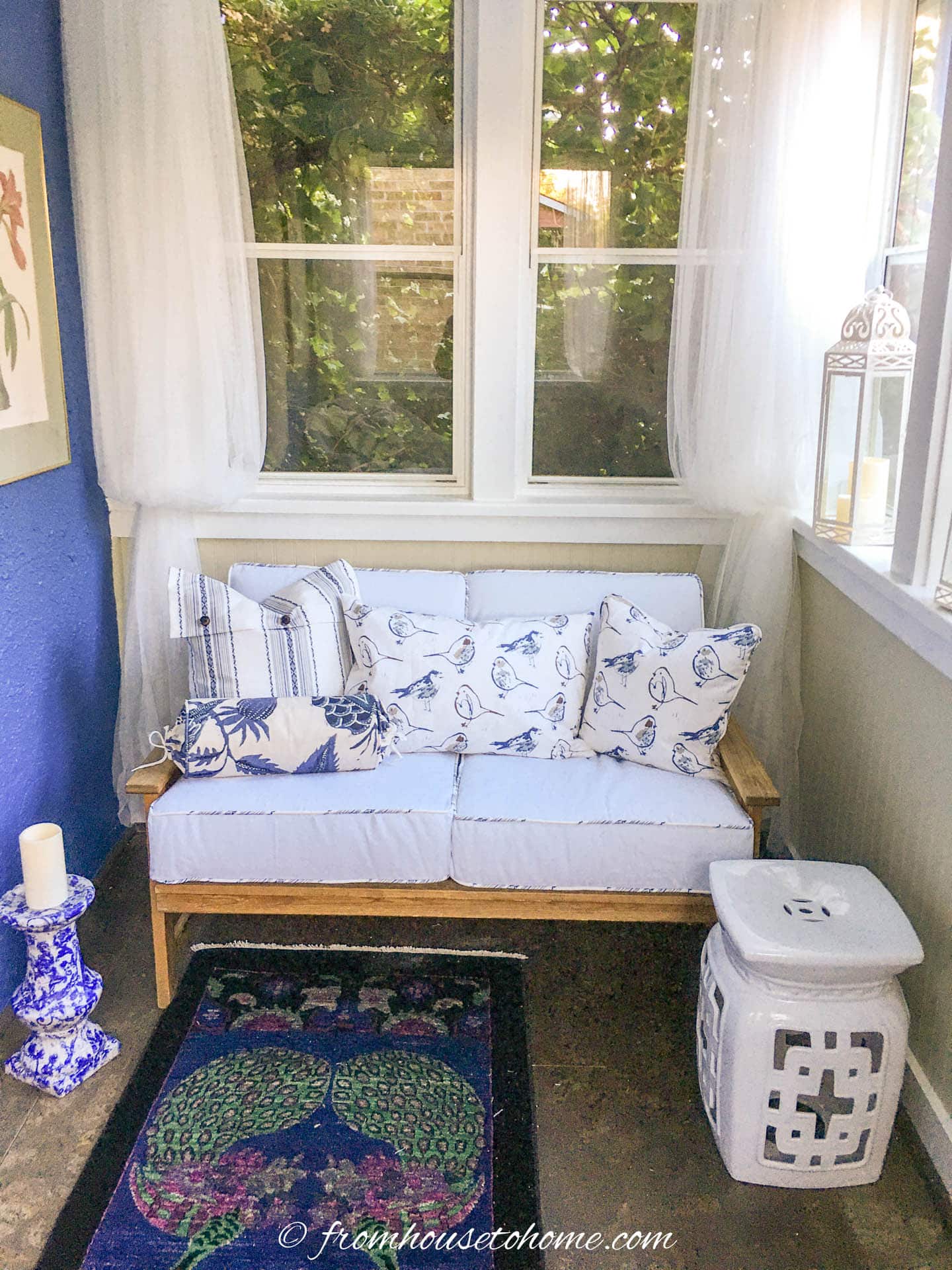 pine loveseat with white box cushions and blue and white throw pillows in a front porch