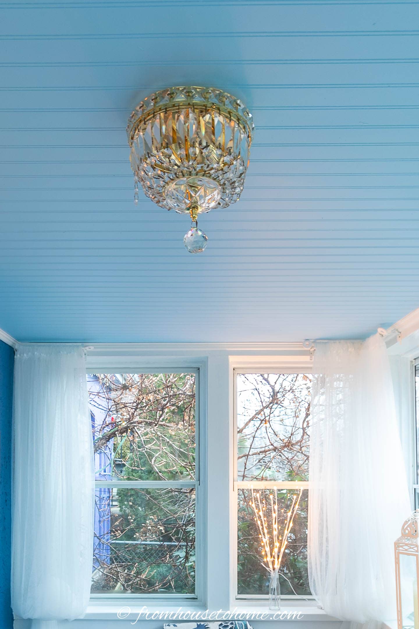 light blue beadboard ceiling with a crystal light fixture