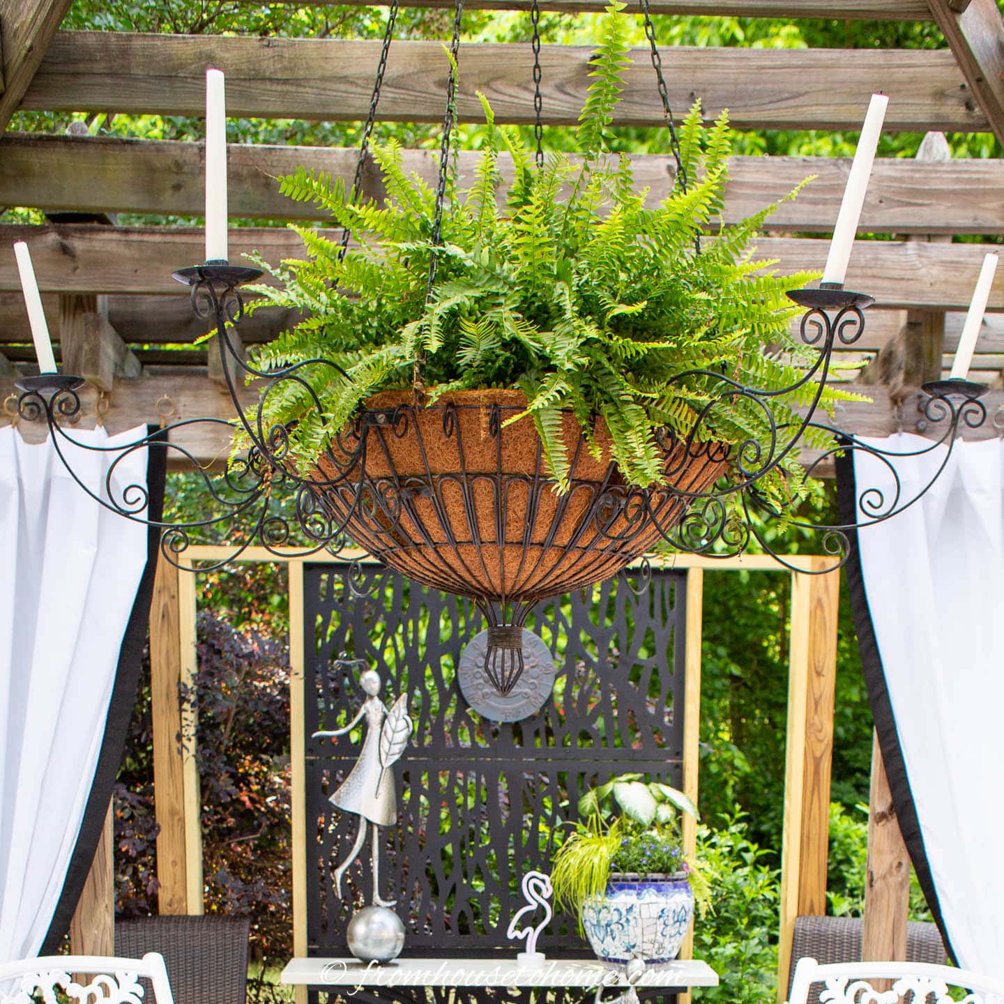 outdoor wrought iron candle chandelier with a fern planted in the middle