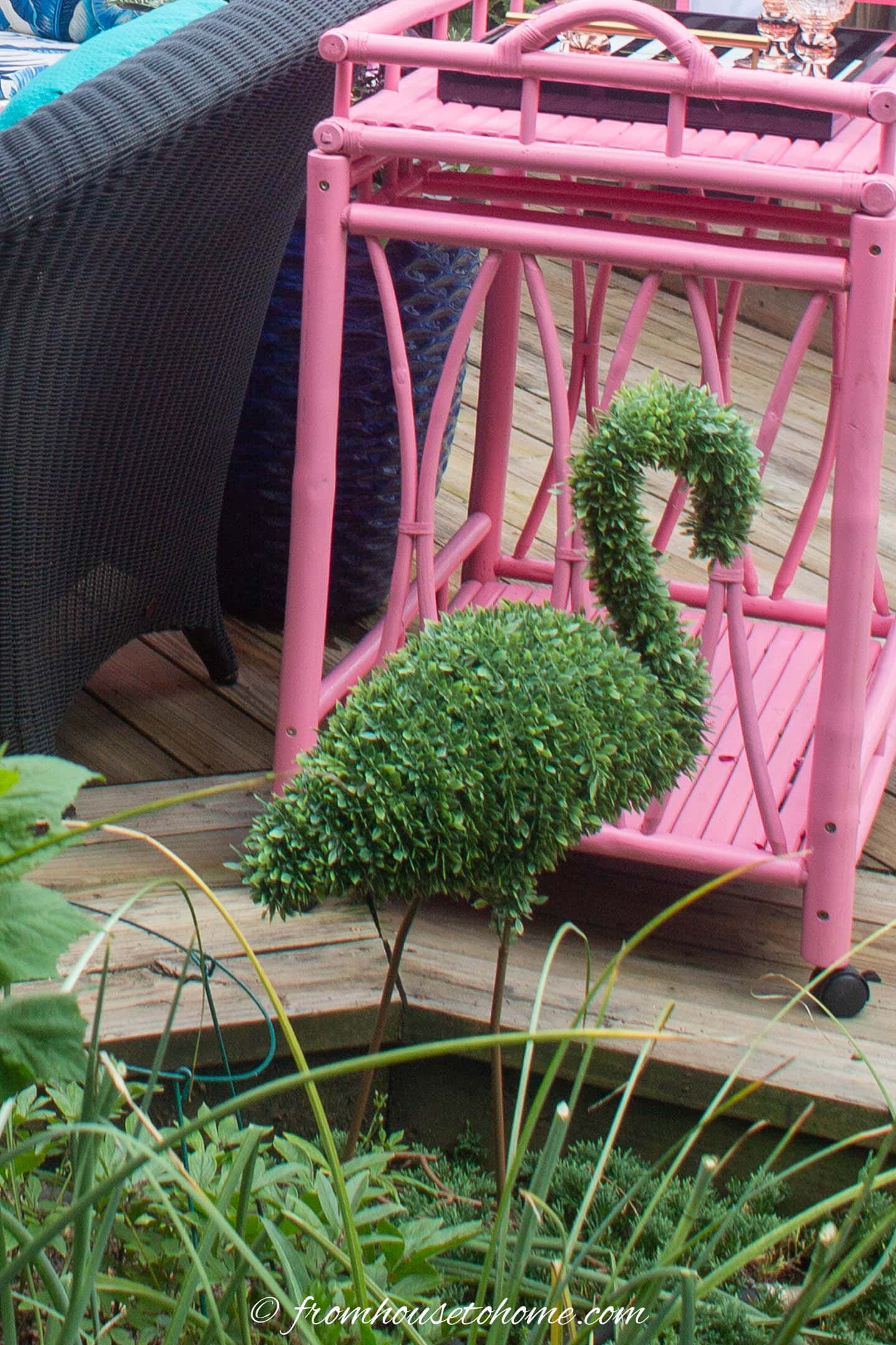 Faux flamingo topiary in front of a pink bar cart