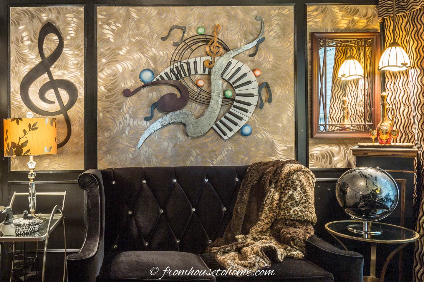 Black and gold wall with music wall sculptures over a black velvet loveseat