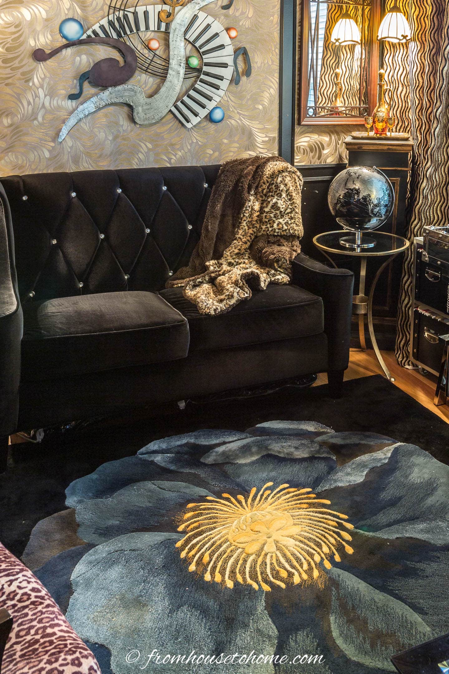 Cozy black velvet loveseat and a plush area rug with a big blue flower on it