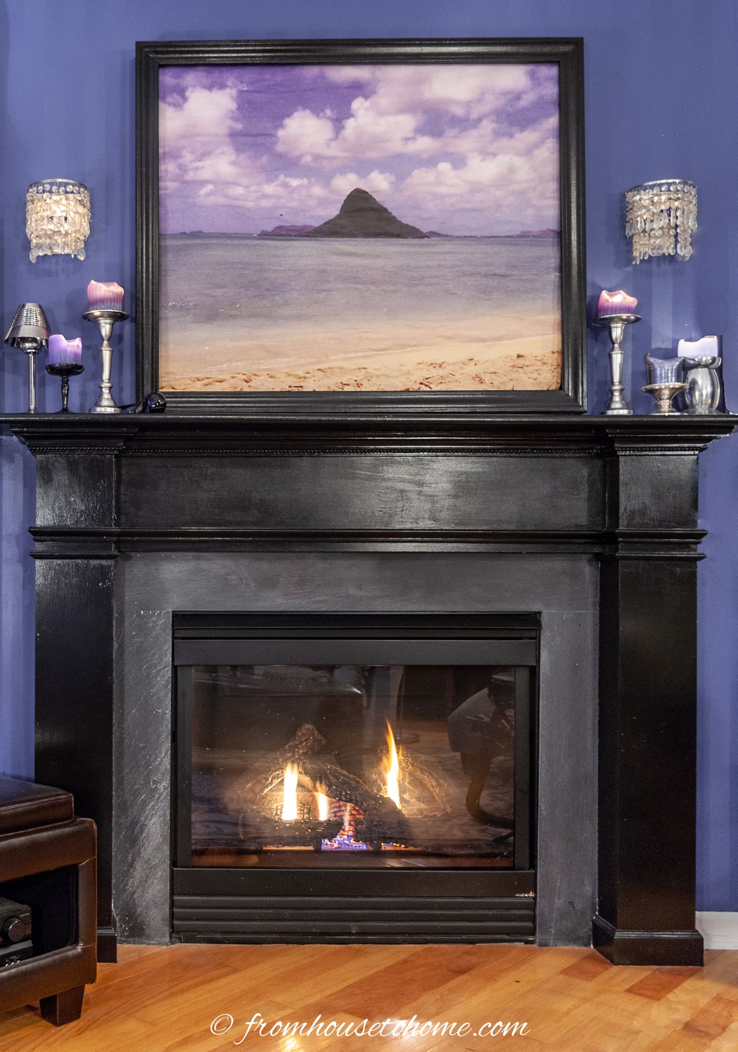 A black DIY fireplace mantel with crown molding with a picture above it.