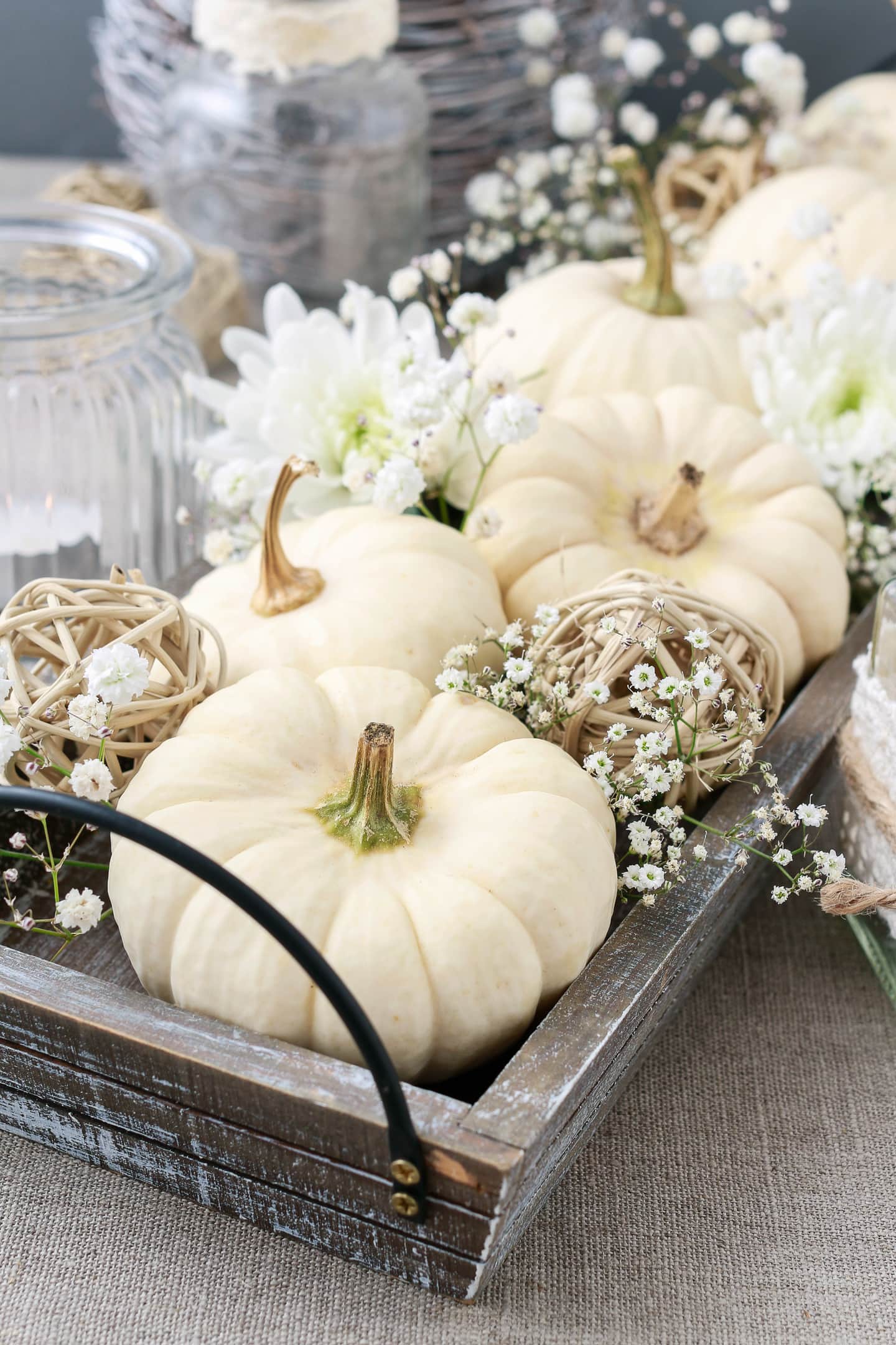 A wooden tray brimming with white pumpkins and flowers, perfect for fall home decor.