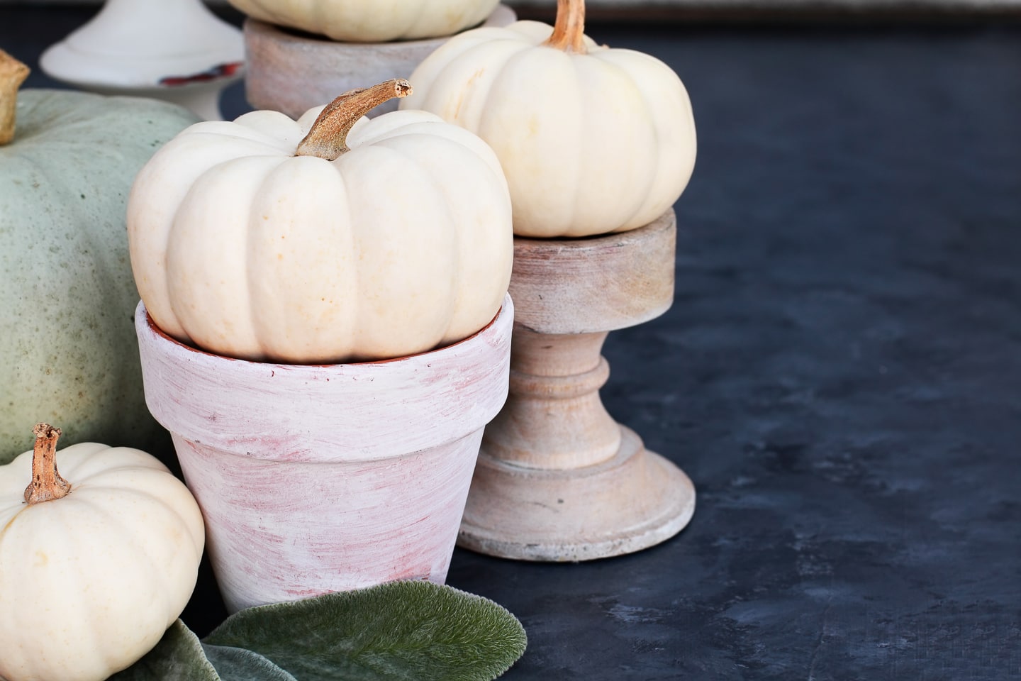 Fall home decor: A group of white pumpkins in pots on a table.