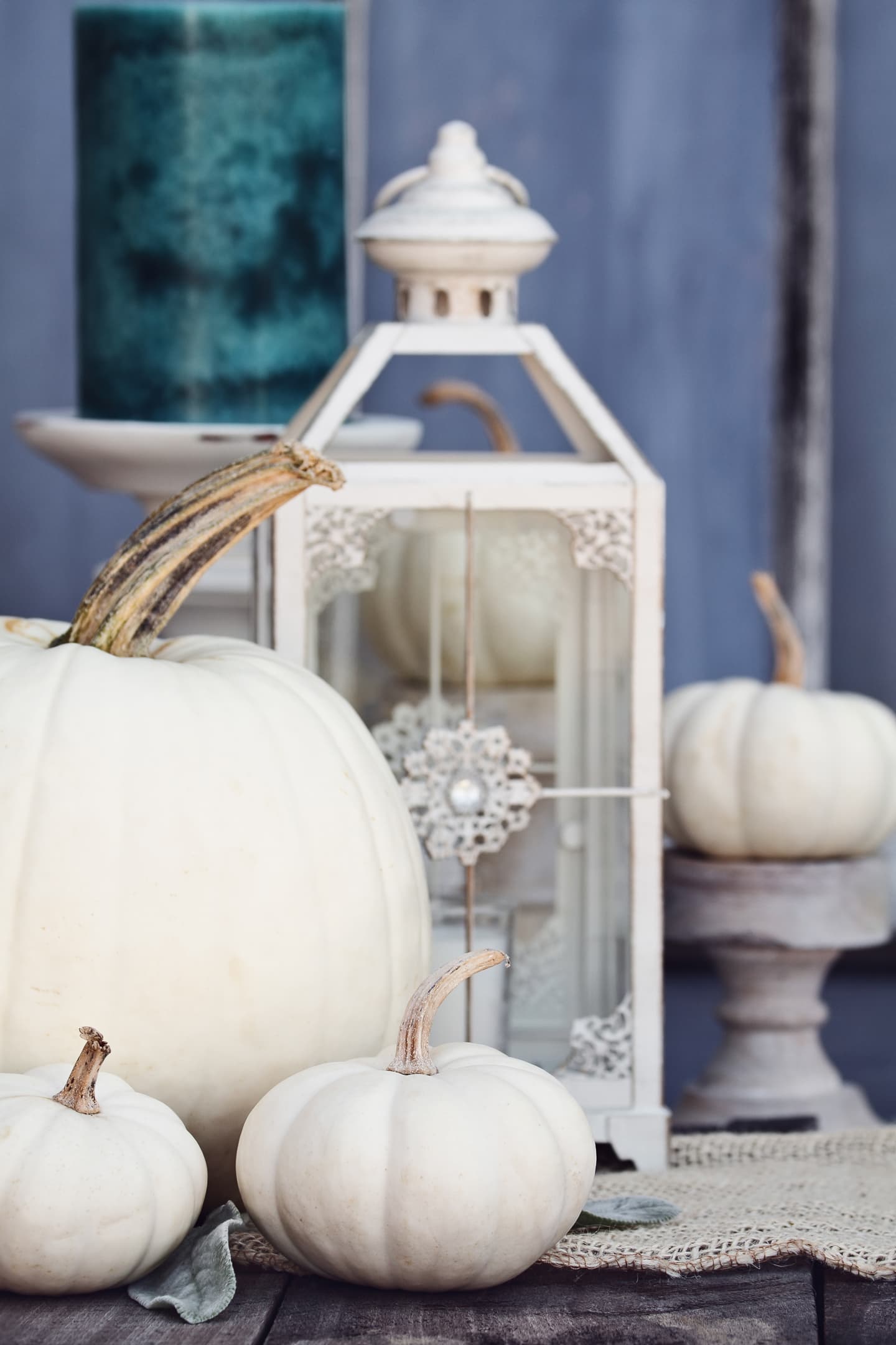 Fall home decor ideas featuring white pumpkins and a lantern on a wooden table.
