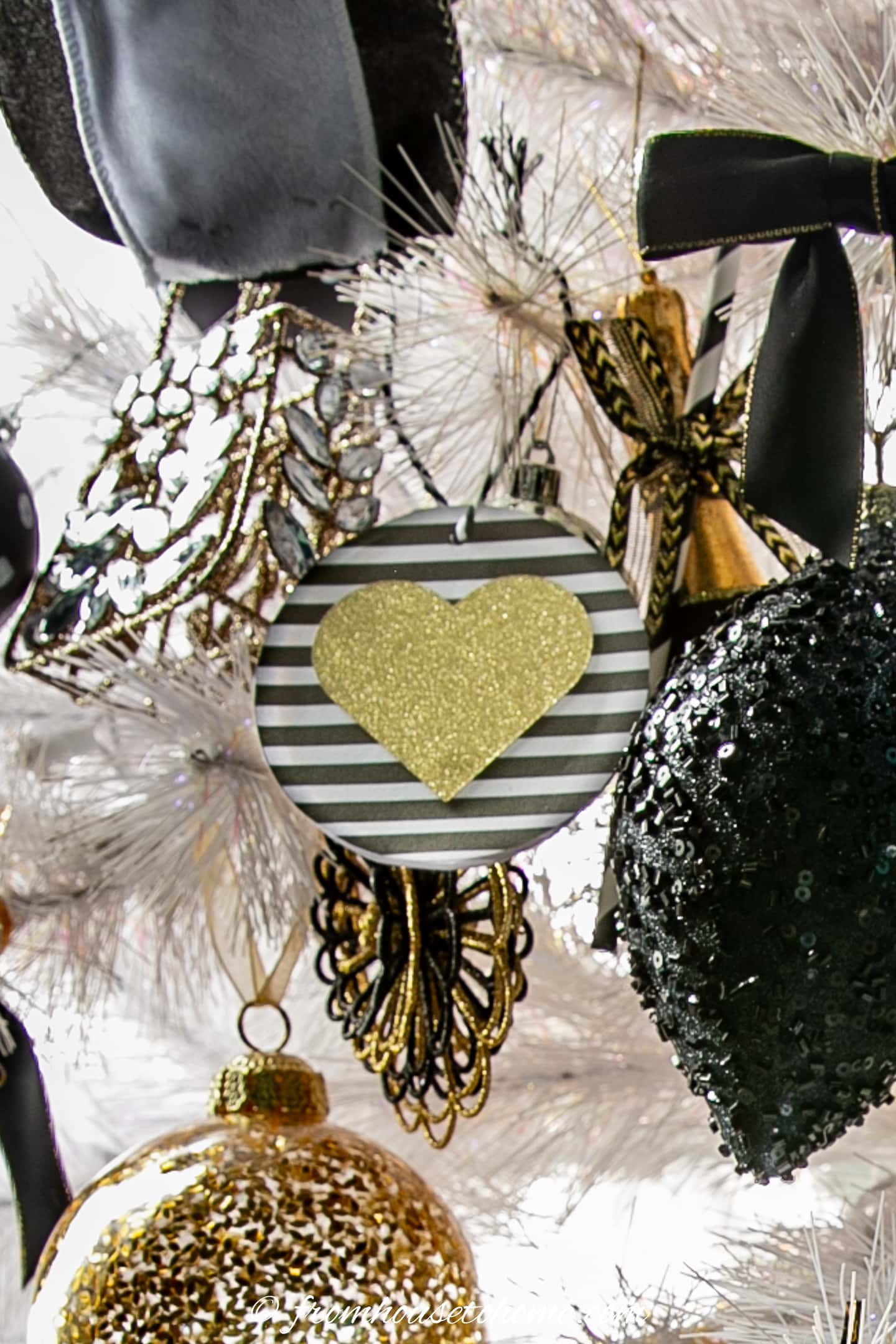 A DIY heart Christmas ornament hung on a white Christmas tree