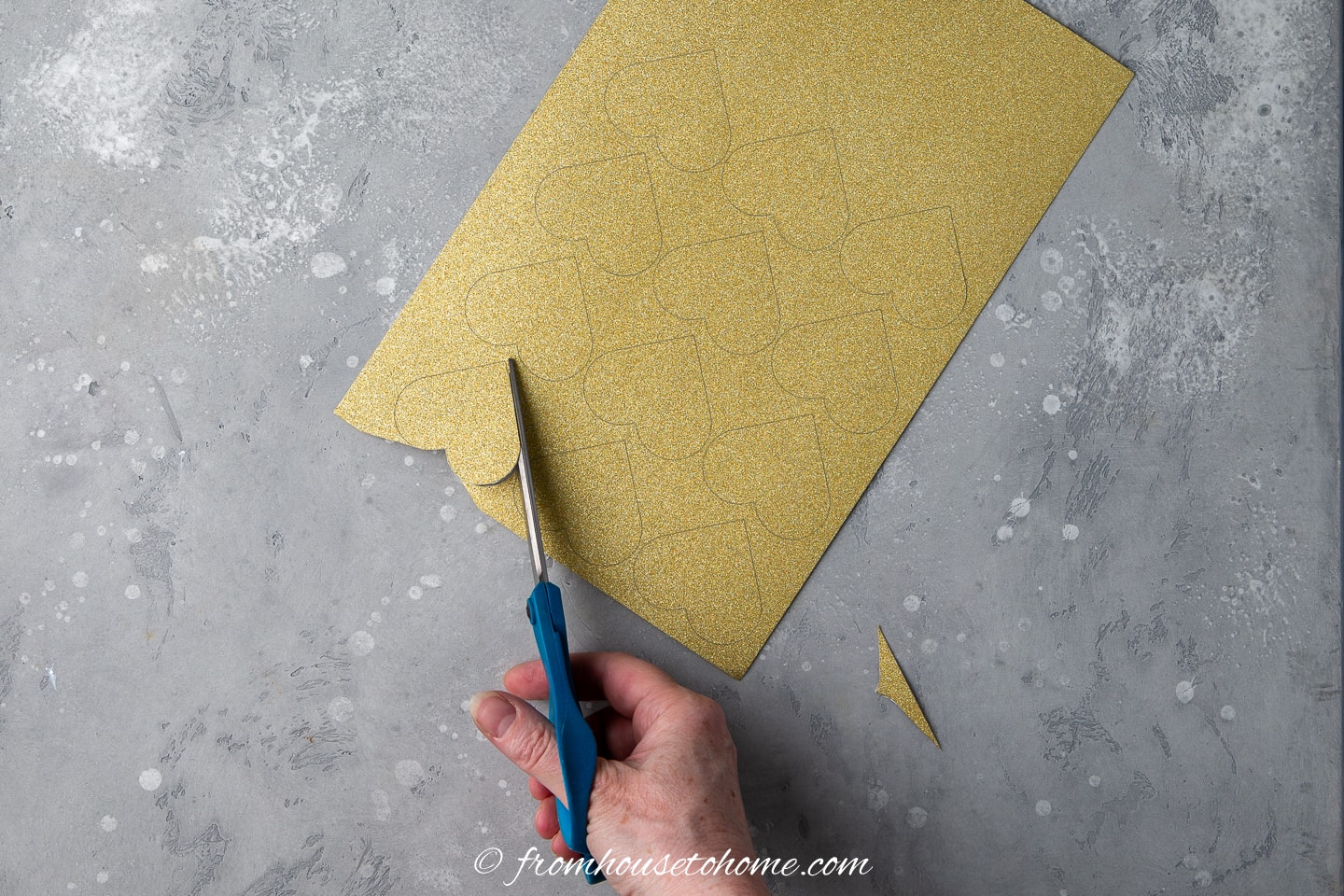 Hearts being cut from gold glitter paper with scissors