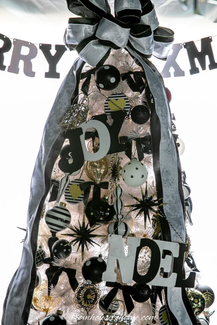 A Christmas tree decorated with DIY letter ornaments in black and white.