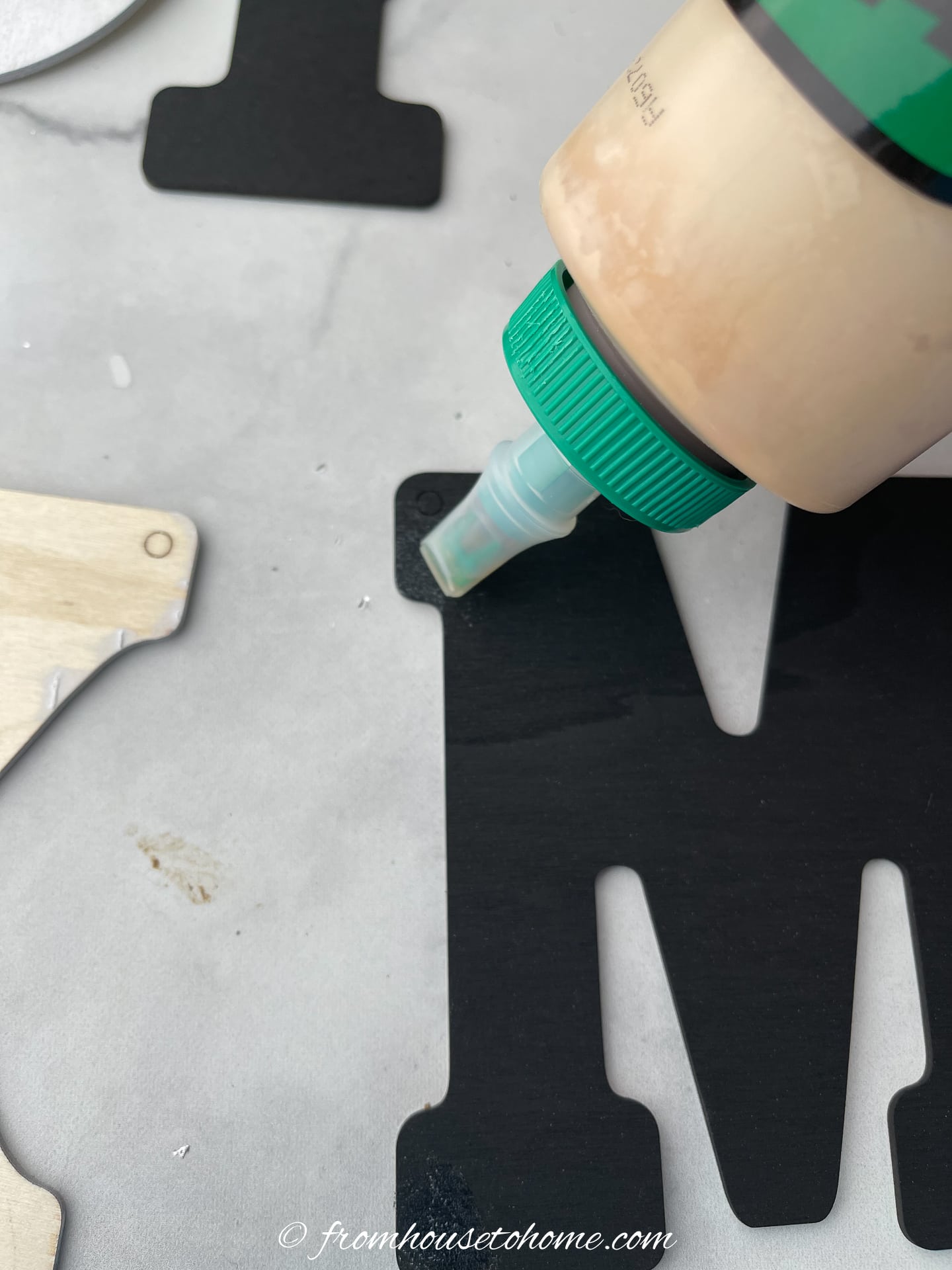 A person is applying glue to a painted wood letter
