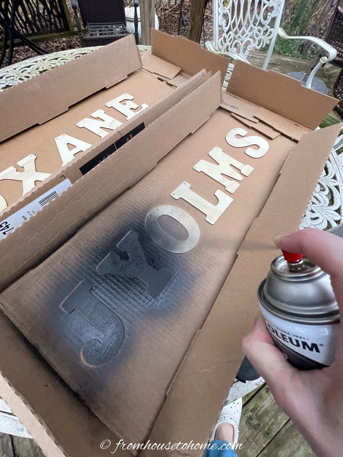 A person painting letter ornaments with black spray paint