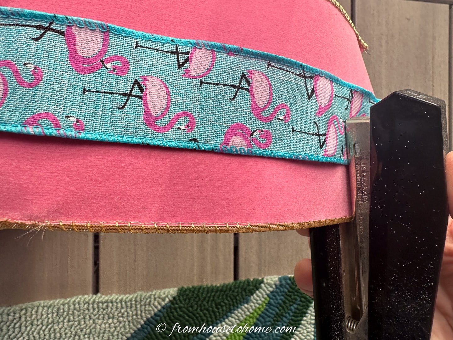 Narrow flamingo ribbon being stapled on top of wider pink ribbon