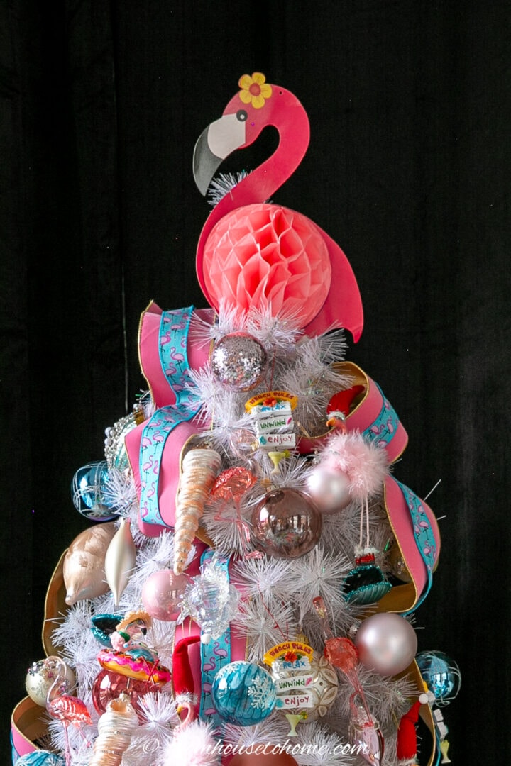 Pink flamingo tree topper on top of a decorated Christmas tree