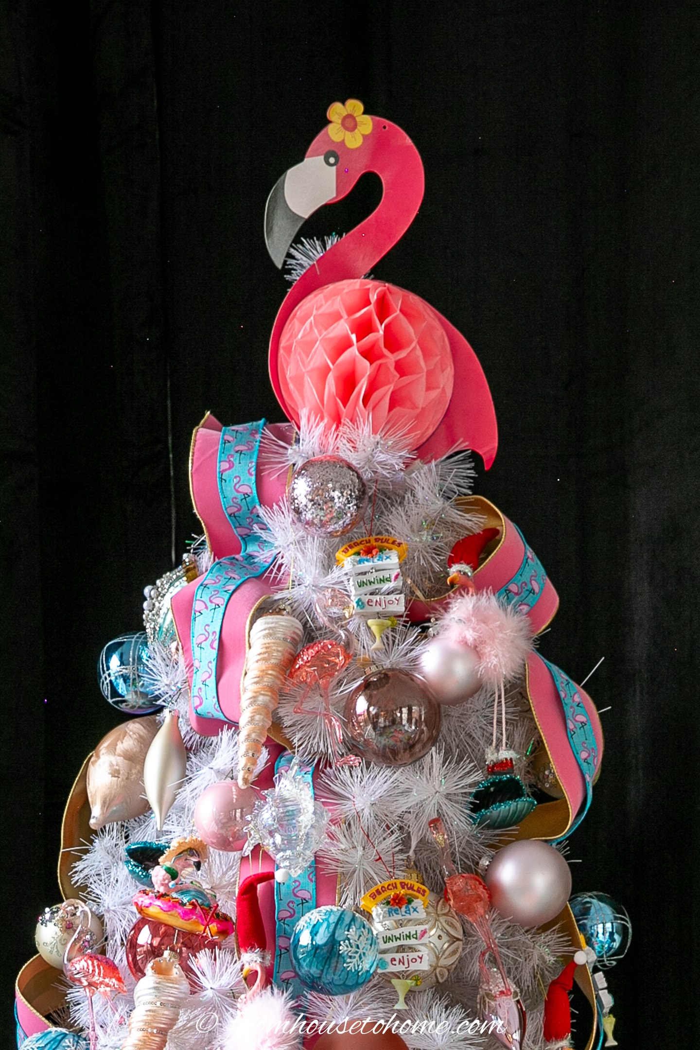 Pink flamingo tree topper on top of a decorated Christmas tree