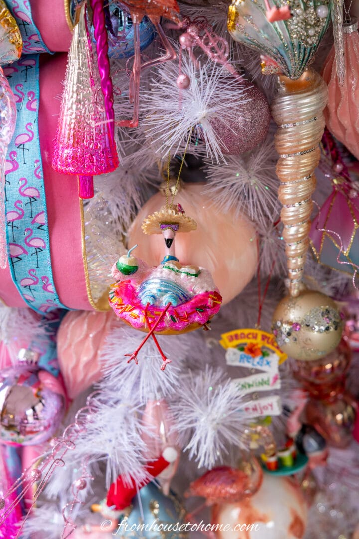 A close up picture of ornaments on a pink flamingo Christmas tree.