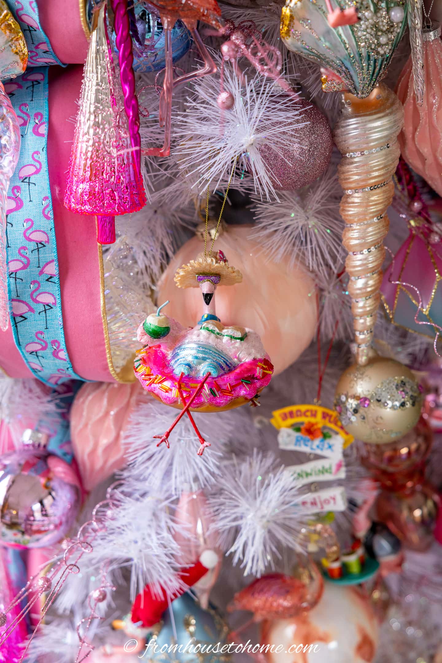 A close up picture of ornaments on a pink flamingo Christmas tree.