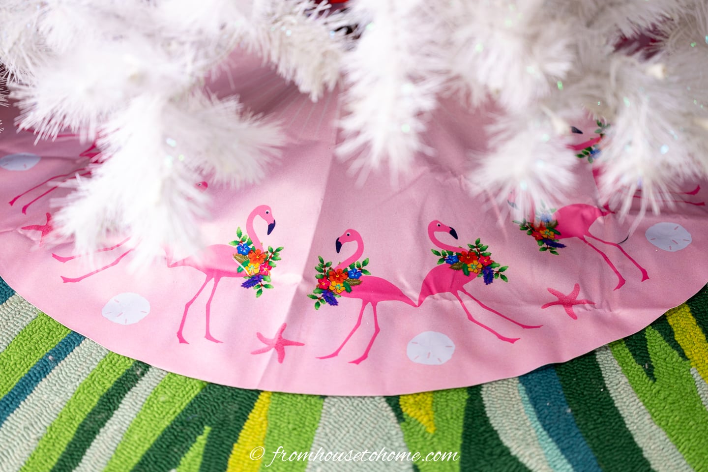 Pink flamingo tree skirt under a white Christmas tree