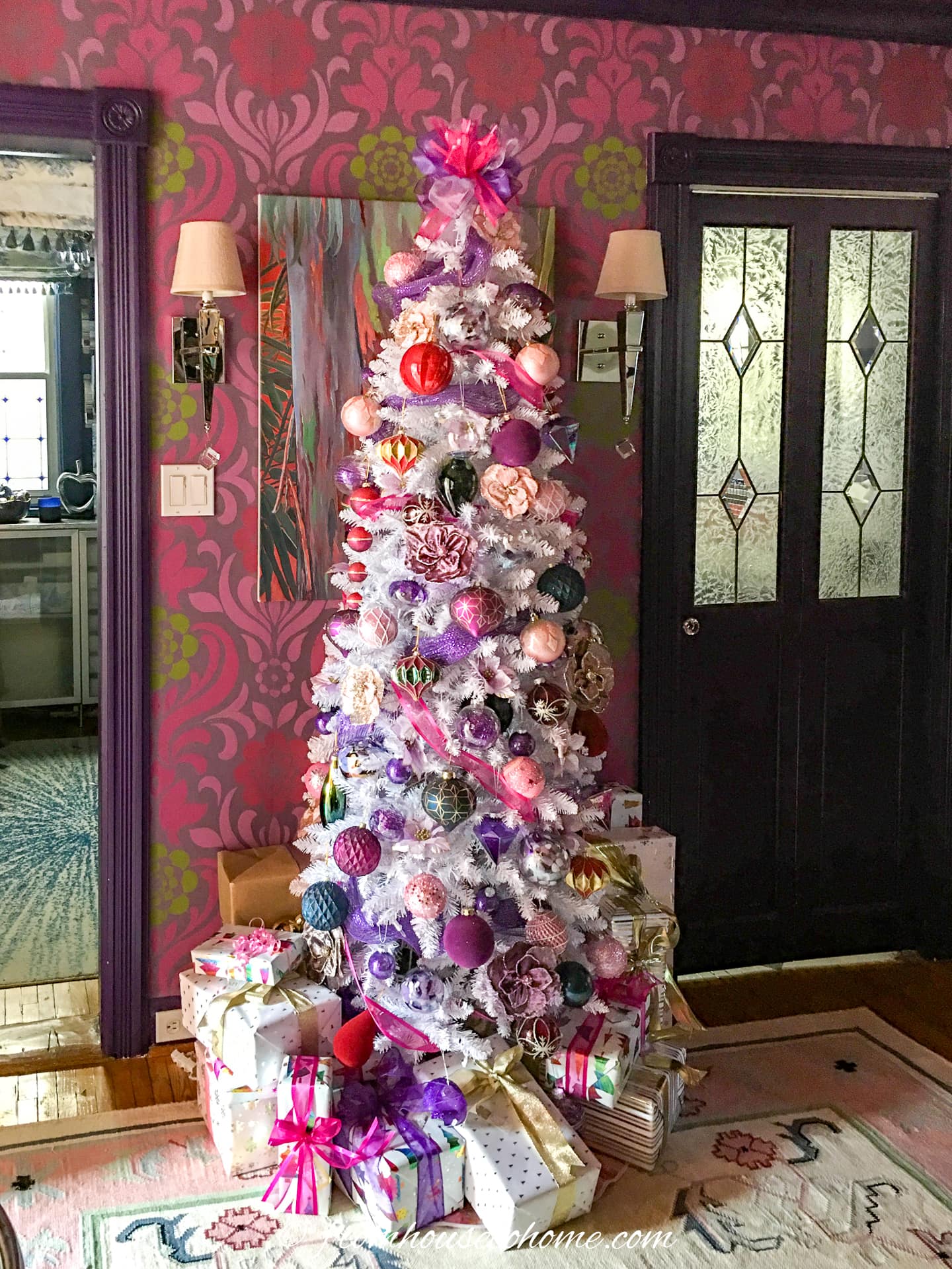 A festive pink and purple Christmas tree with lots of presents at the bottom