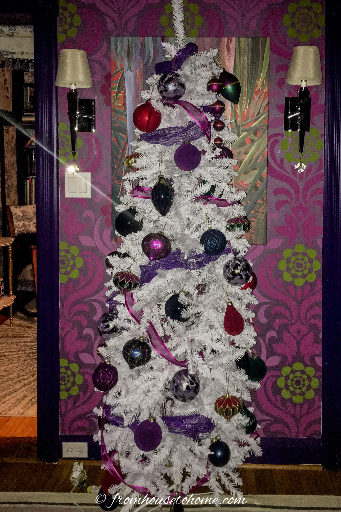 A white Christmas tree with large pink and purple ornaments on it