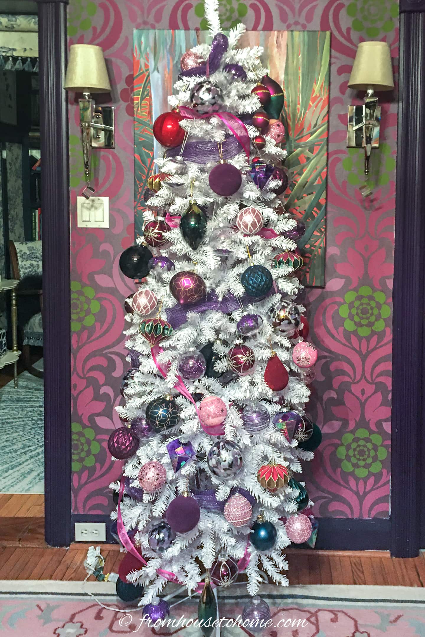 A white Christmas tree decorated with purple and pink ribbon and ornaments.