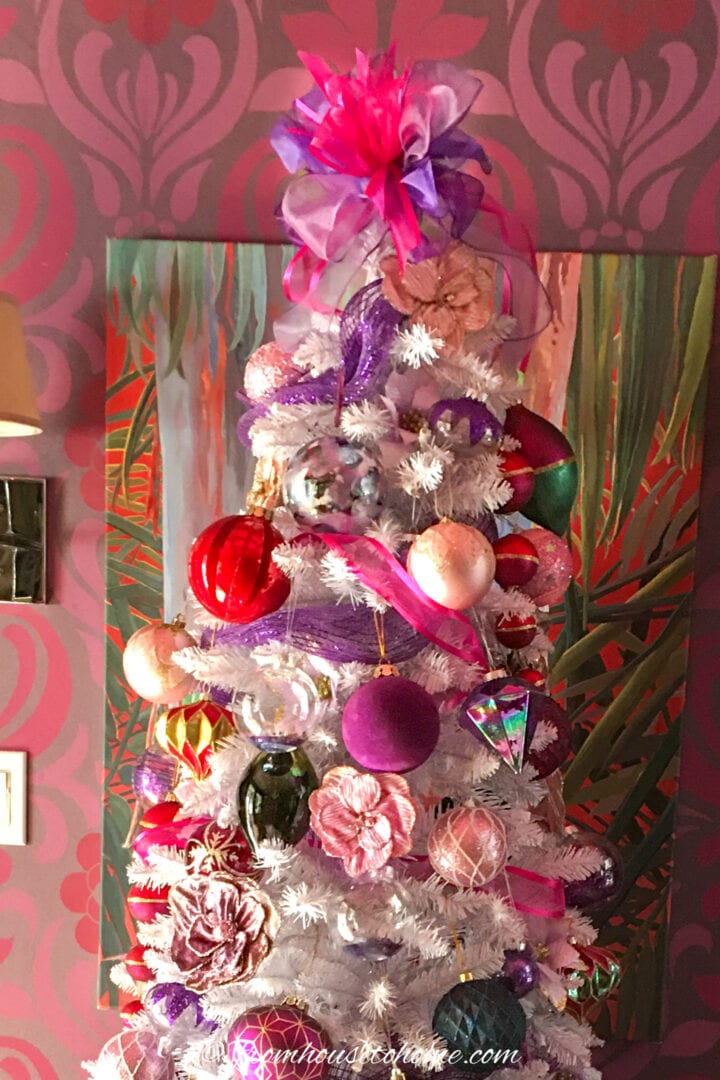 A purple and pink Christmas tree with a bow tree topper