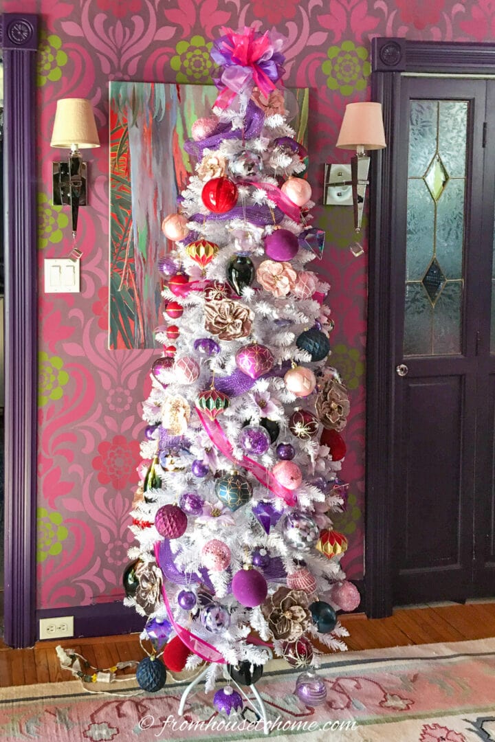 A pink and purple room adorned with a beautiful white Christmas tree.