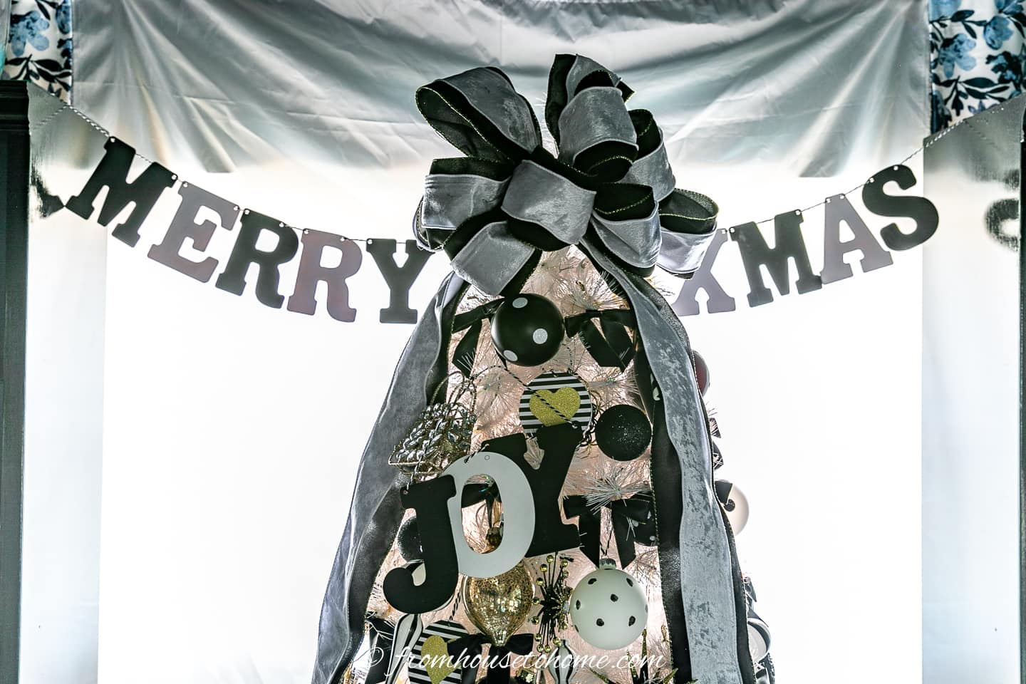 Merry Xmas banner behind a black and white Christmas tree