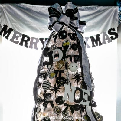 The top of a white Christmas tree with black decorations.