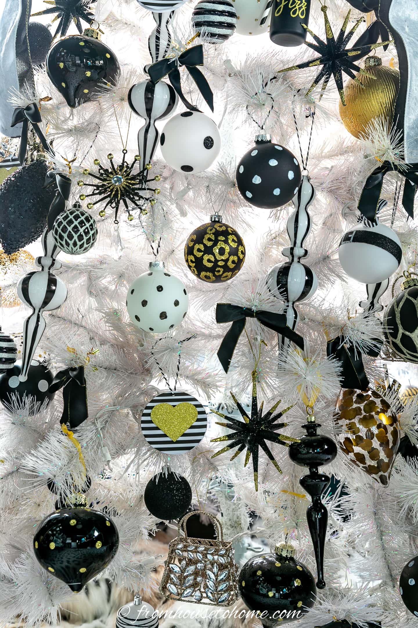 A close up picture of a white Christmas tree with black ornaments.