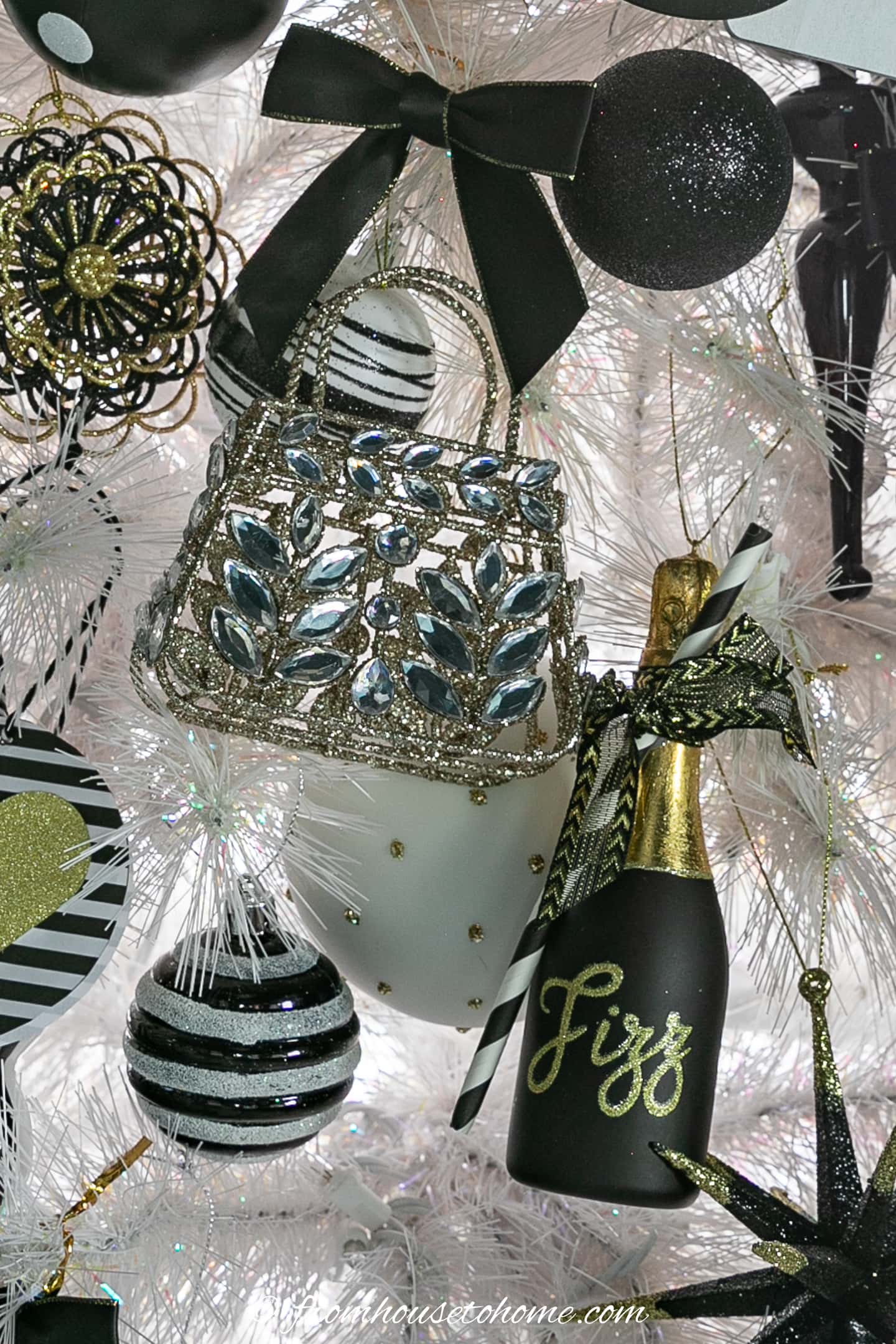 A close up picture of a white Christmas tree with black decorations.
