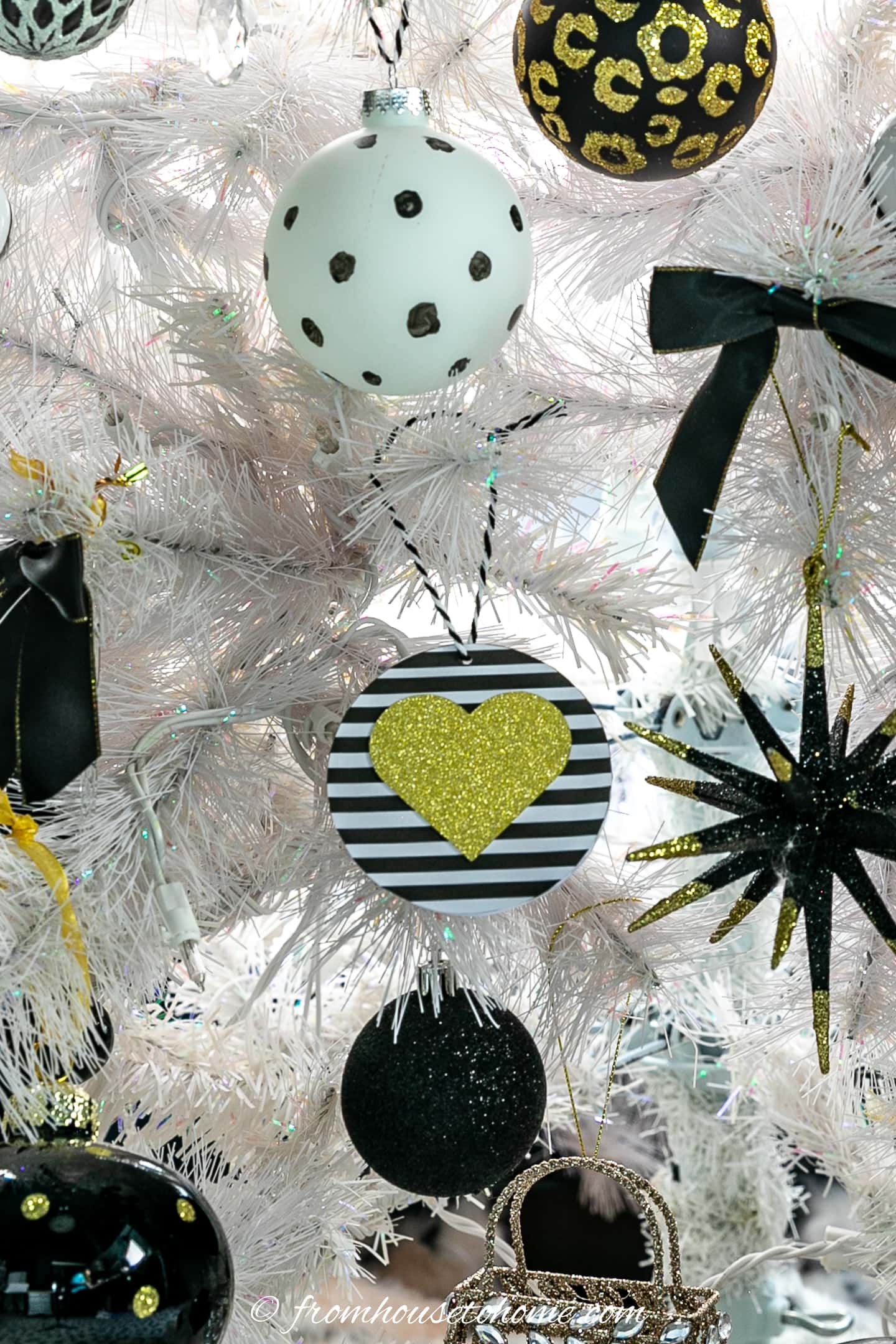 White Christmas tree decorated with a black and white striped round ornament with a gold heart in the middle