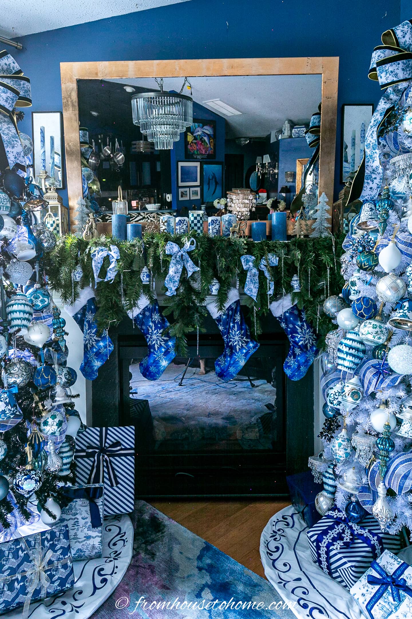 Simple blue and white garland on a fireplace mantel between 2 Christmas trees