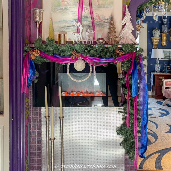Evergreen garland with pink and purple ribbon over an electric fireplace in a small room