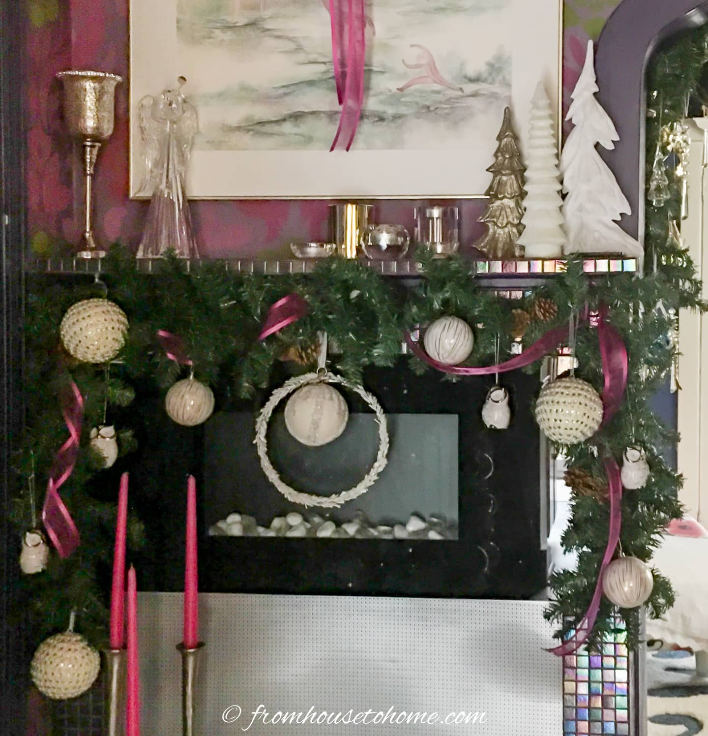 Fireplace mantel decorated with a garland with pink ribbon and white ornaments