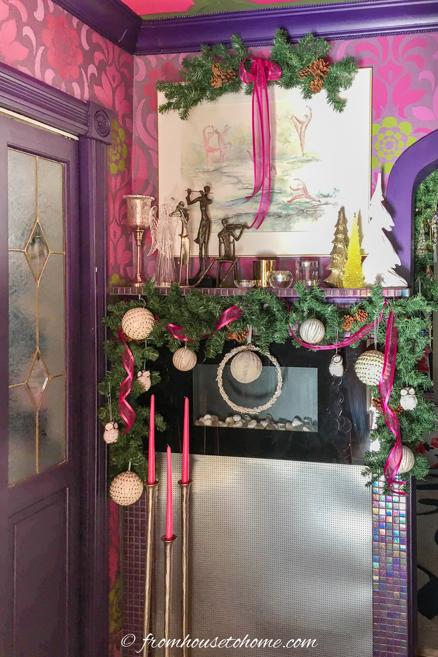 Tall candleholders in front of a fireplace decorated for Christmas