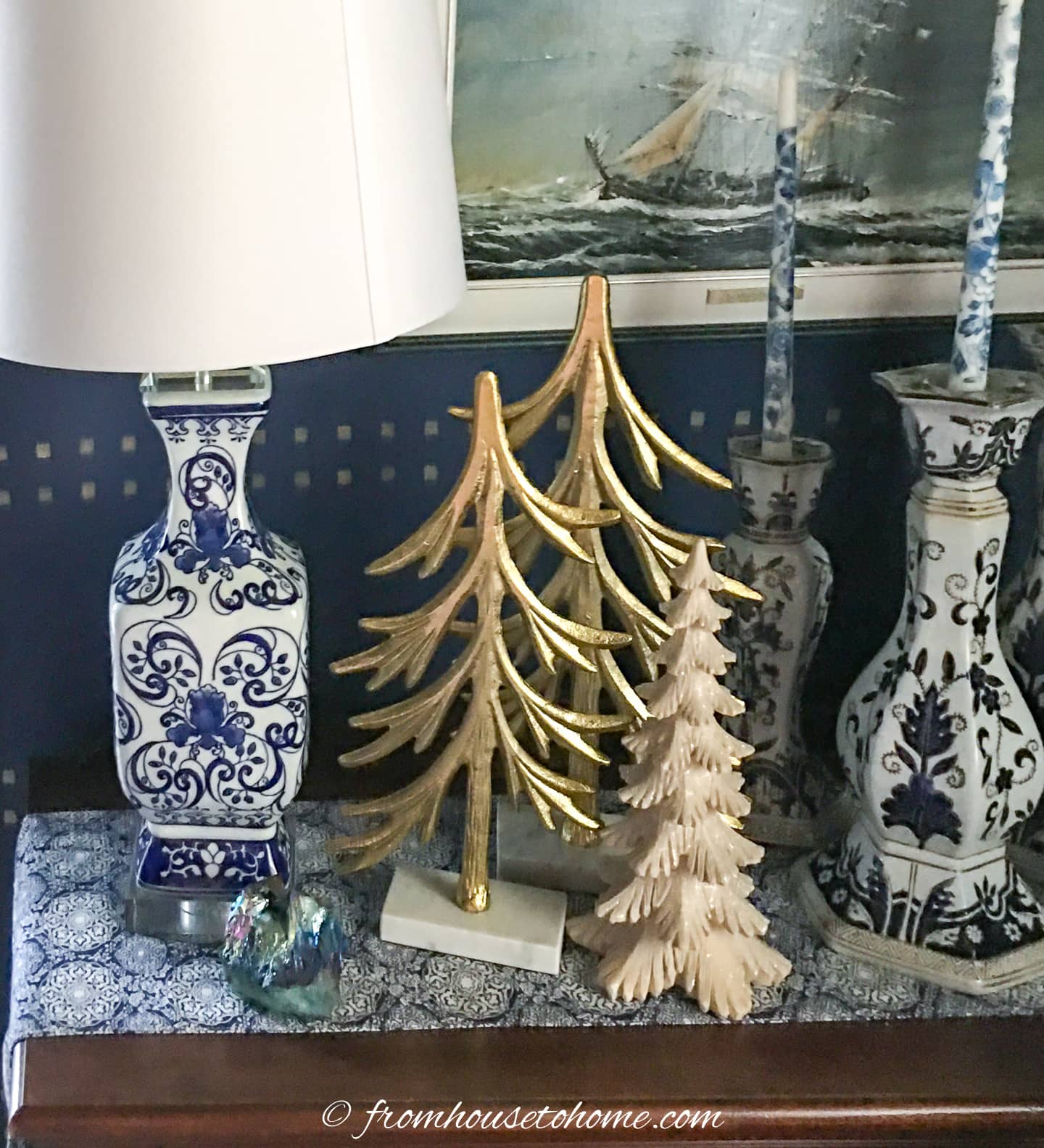 3 mini trees on a table with a lamp and candles