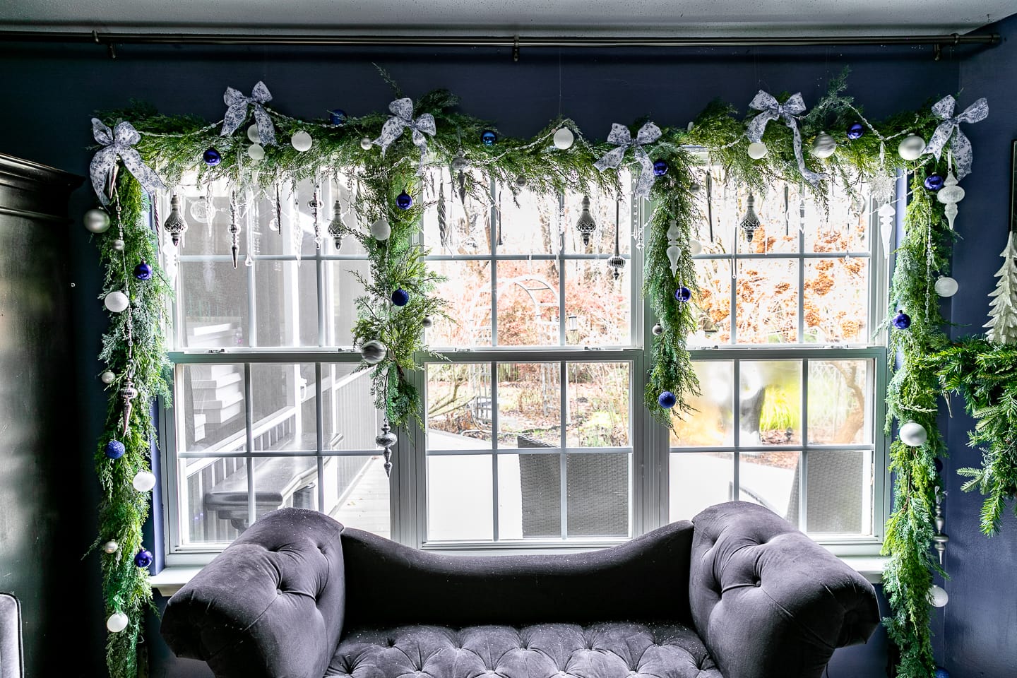 DIY Christmas window garland decorated with blue and white ornaments, glass finials and blue and white bows