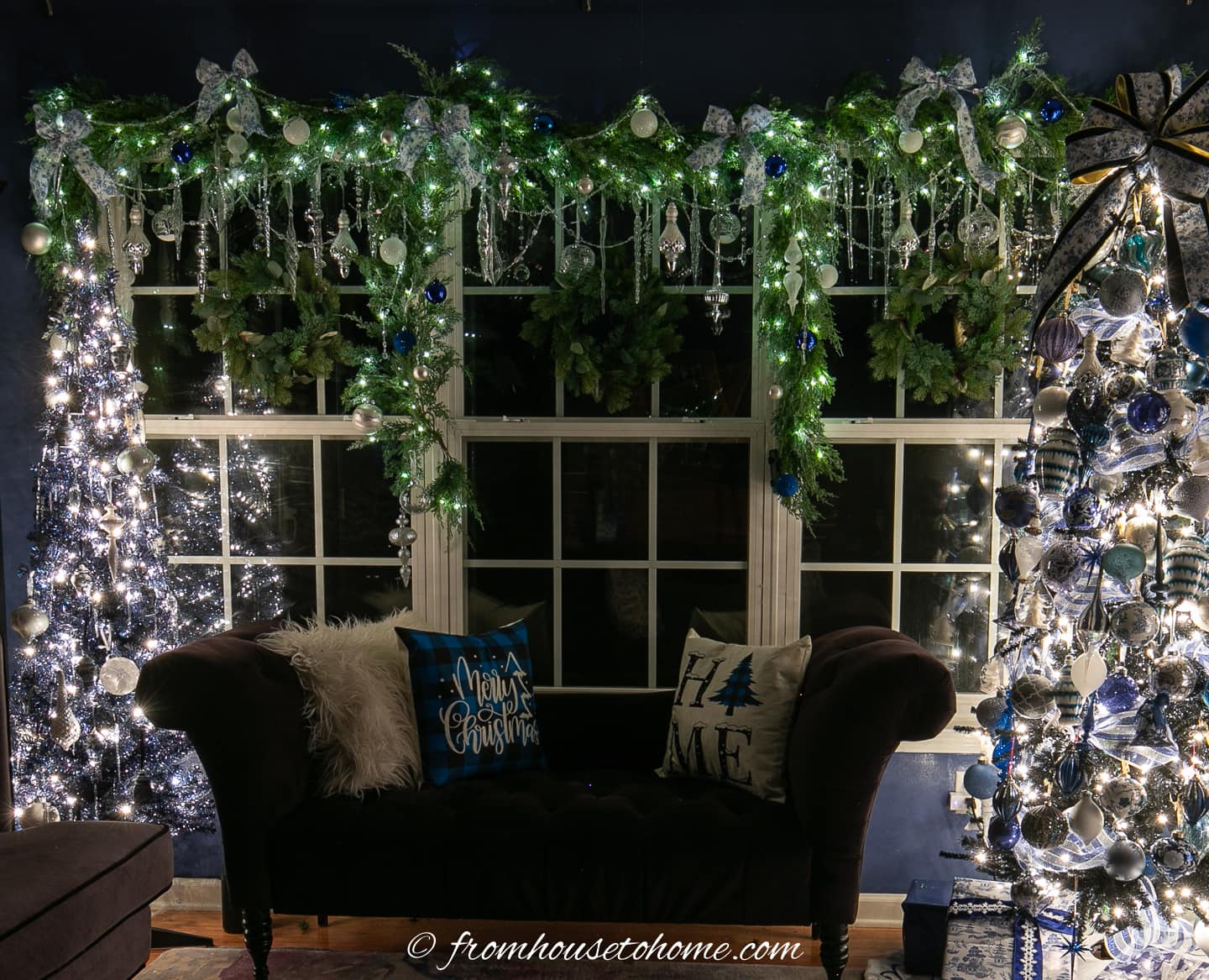 DIY Christmas window garland at night with two Christmas trees