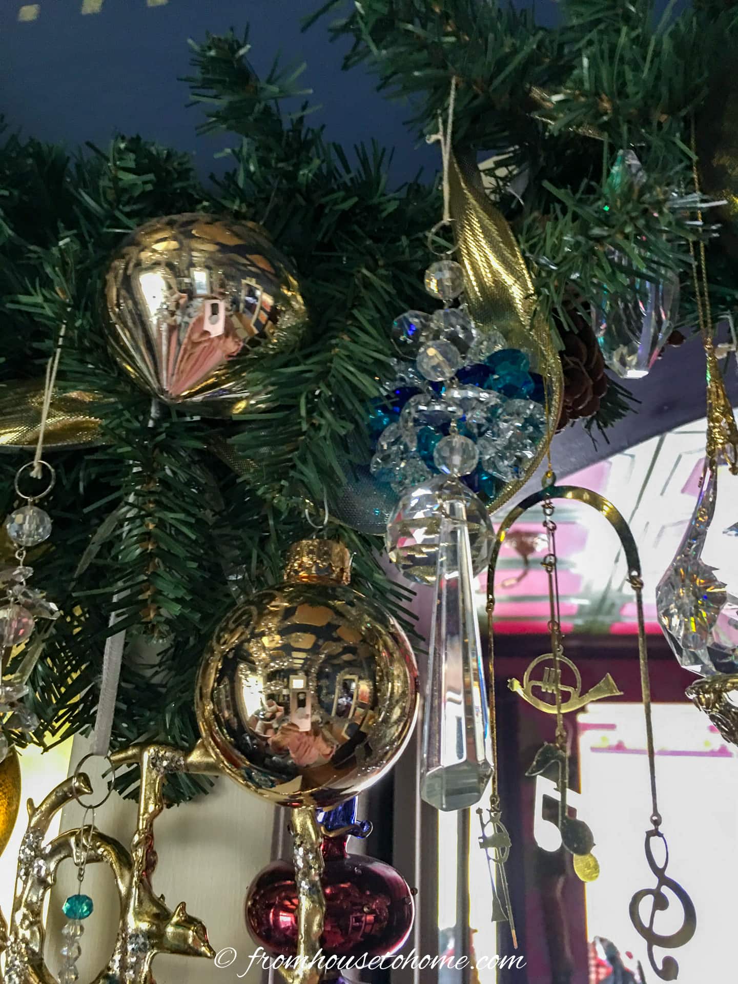 Gold ornaments hung on a Christmas garland above a doorway