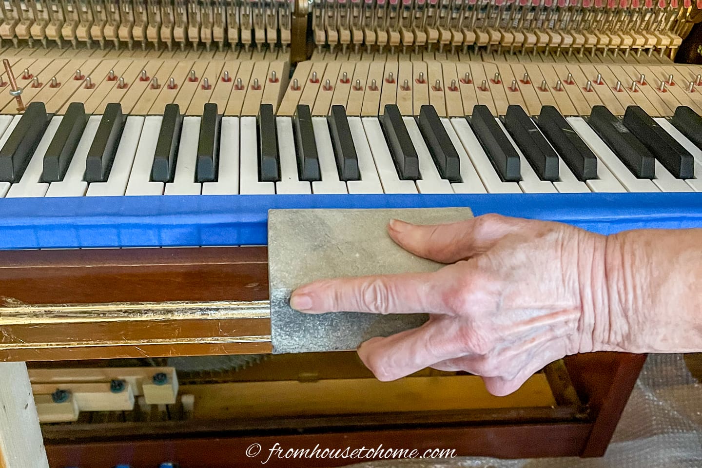 piano being sanded with a sanding block