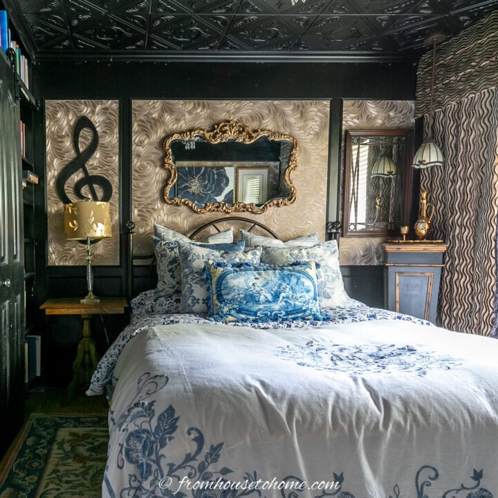 Small bedroom with black walls, gold wallpaper, and blue and white bedding