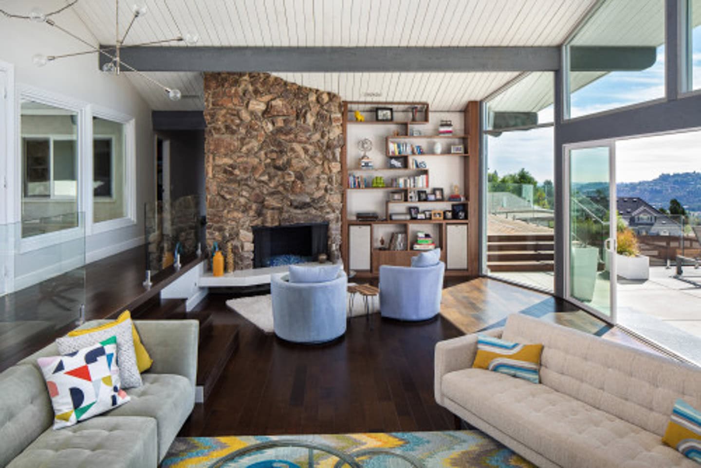 Two chairs set up in front of an angled fireplace with a seating area behind them