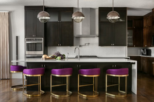 Black kitchen with white marble countertops and fuchsia chairs around the island