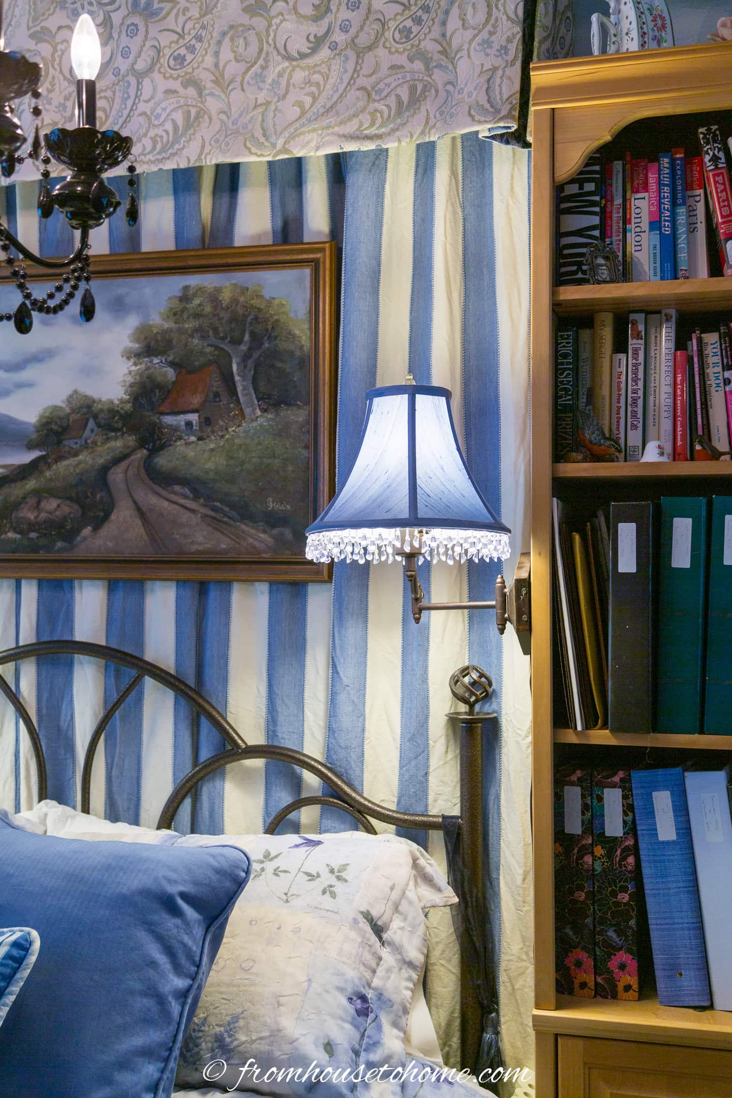 A blue swing-arm lamp with beaded trim installed on a bookcase beside the bed