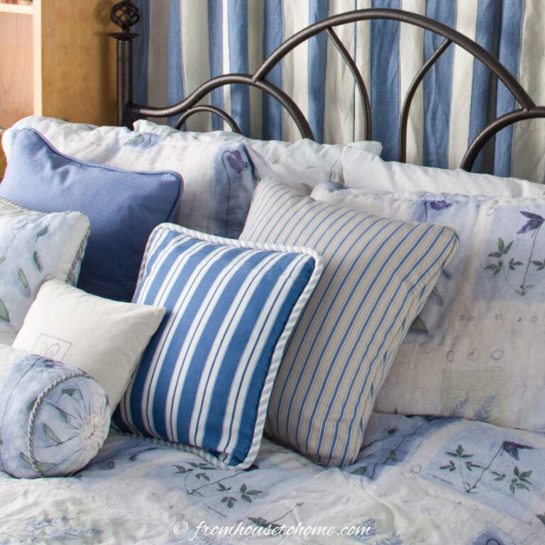Blue and cream cushions on a wrought iron bed