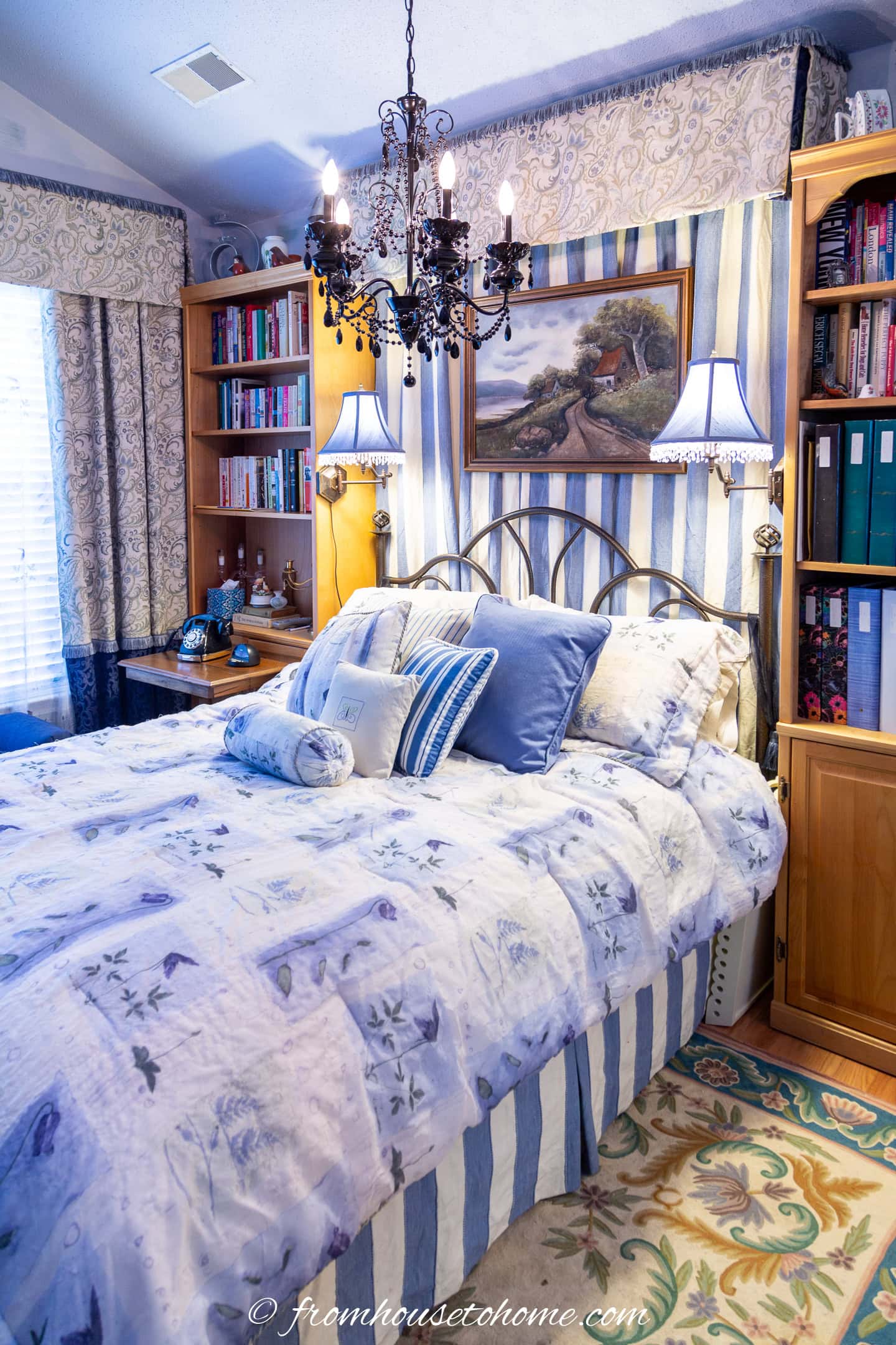 A guest room bed with blue and cream bedding and bookshelves on either side