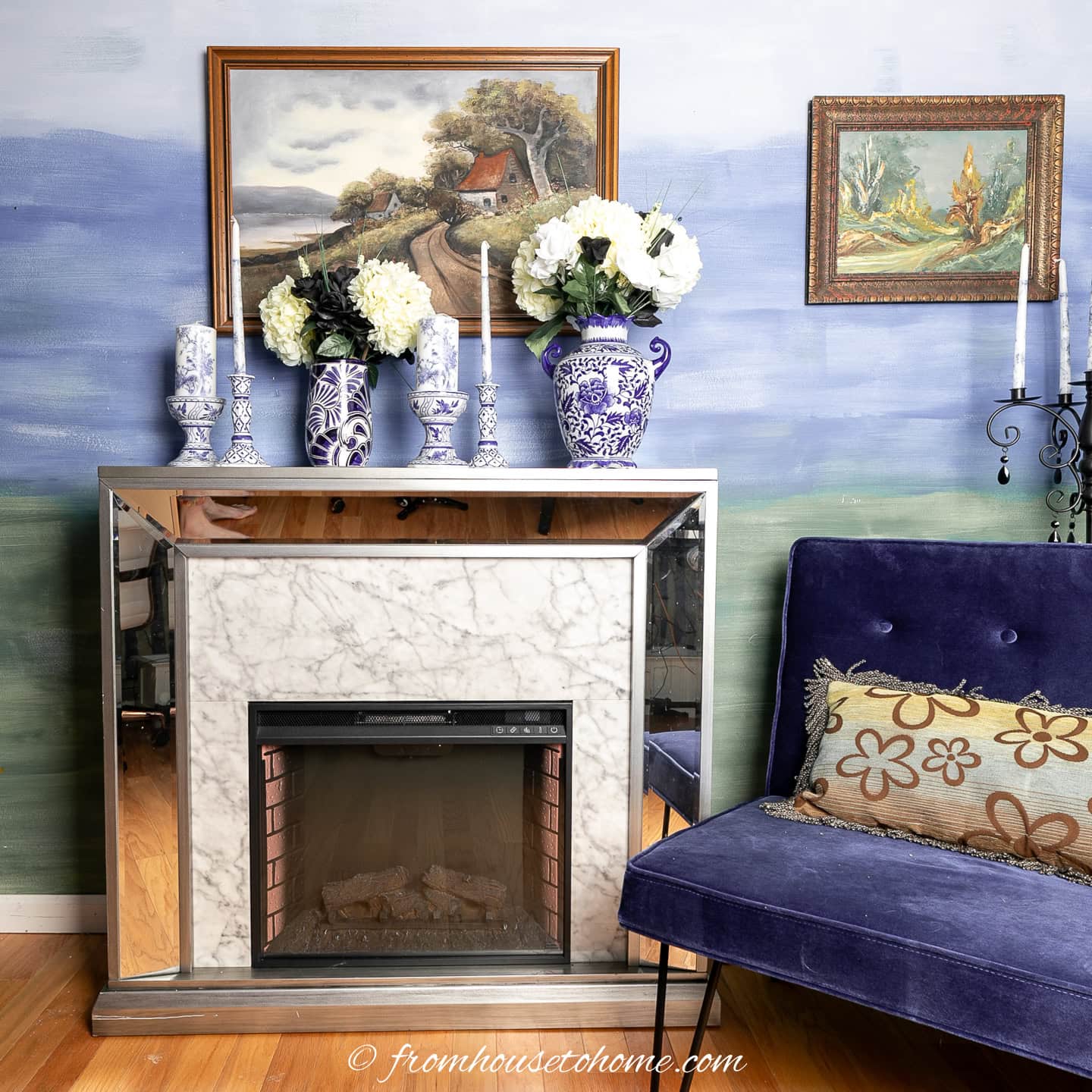 An electric fireplace and blue chair in front of an ombre wall