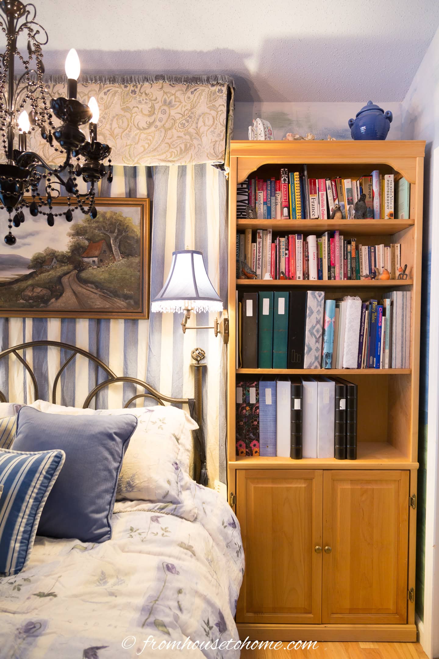 A bookshelf beside the bed in a blue and cream guest bedroom
