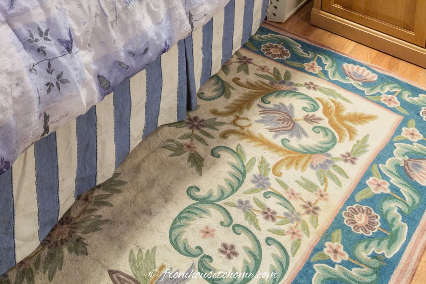A close up of a floral area rug in a cream and blue guest bedroom