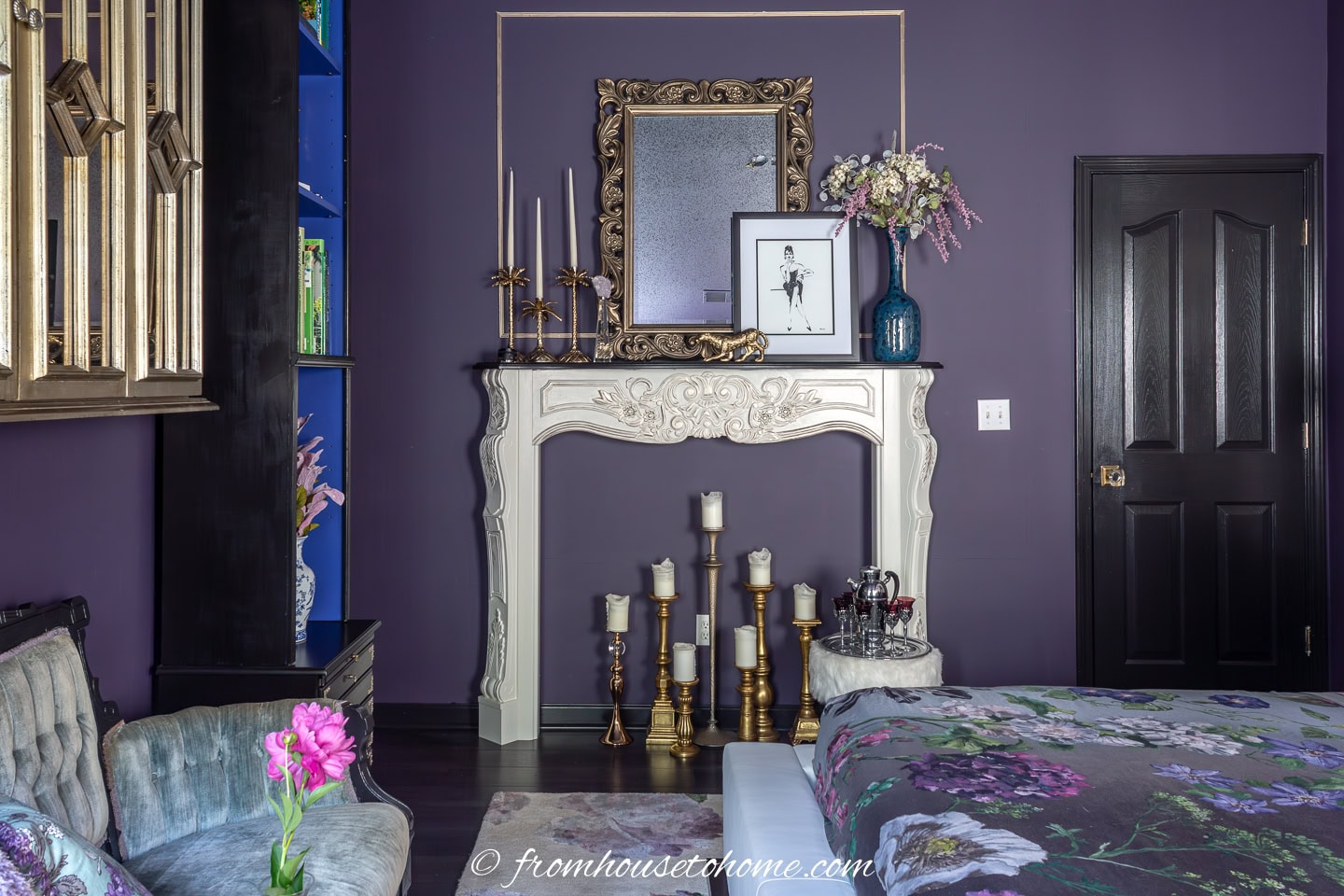 A faux fireplace with gold accessories in a dark purple bedroom